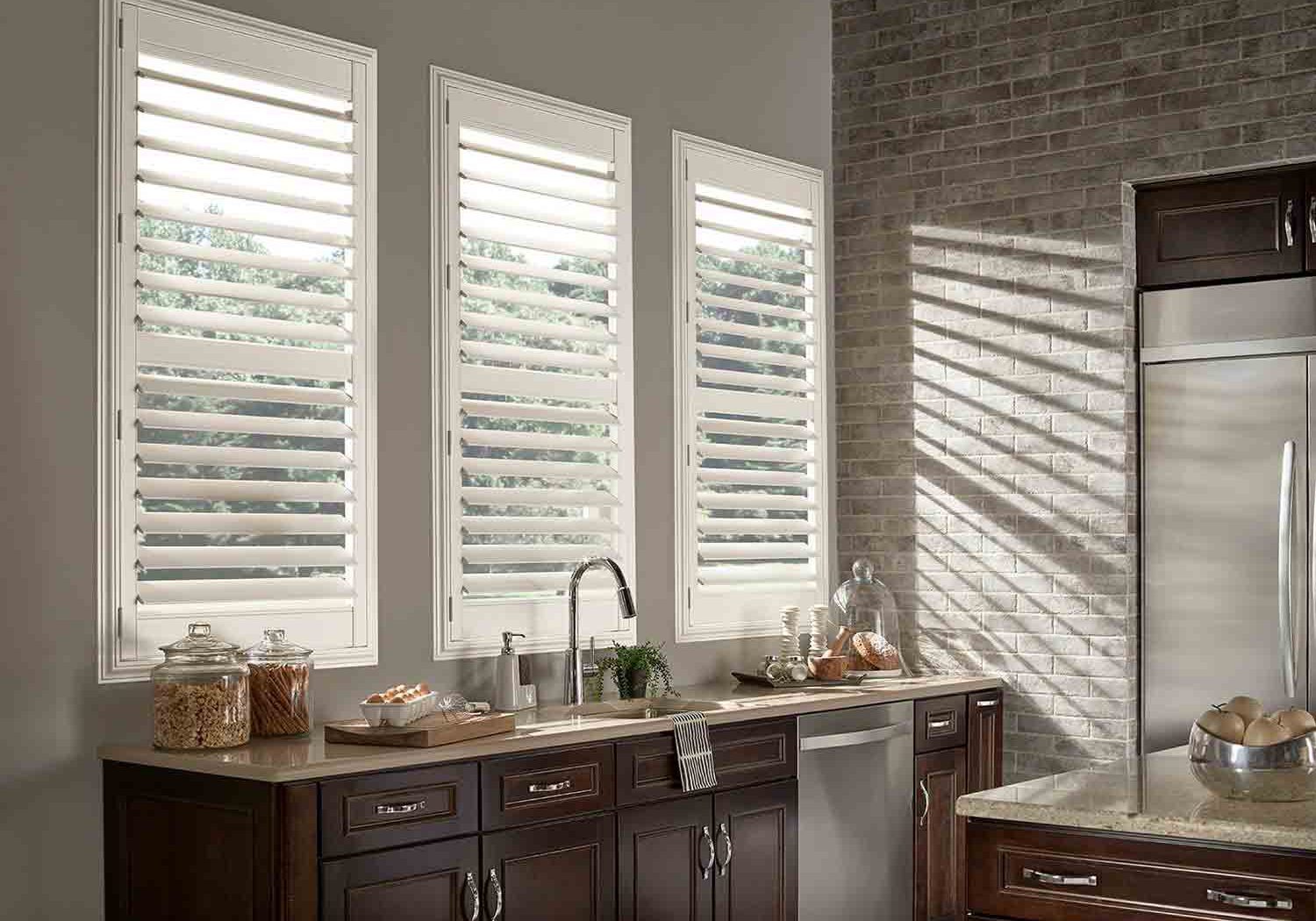 White vinyl shutters installed over three kitchen windows