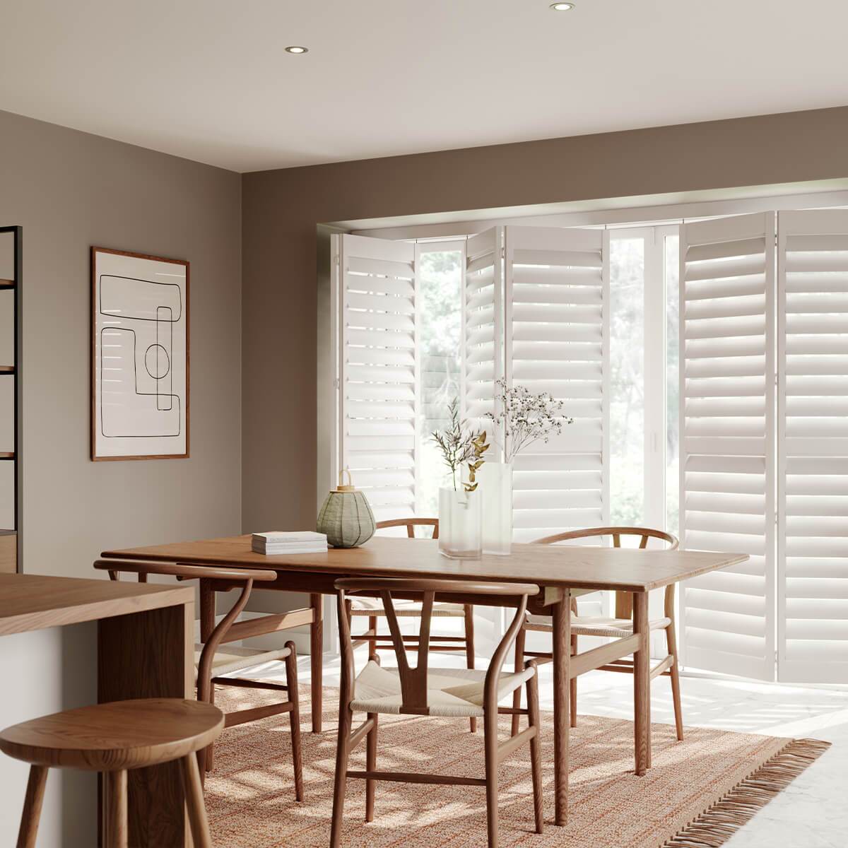 White bi-fold shutters across a wide dining-room patio door