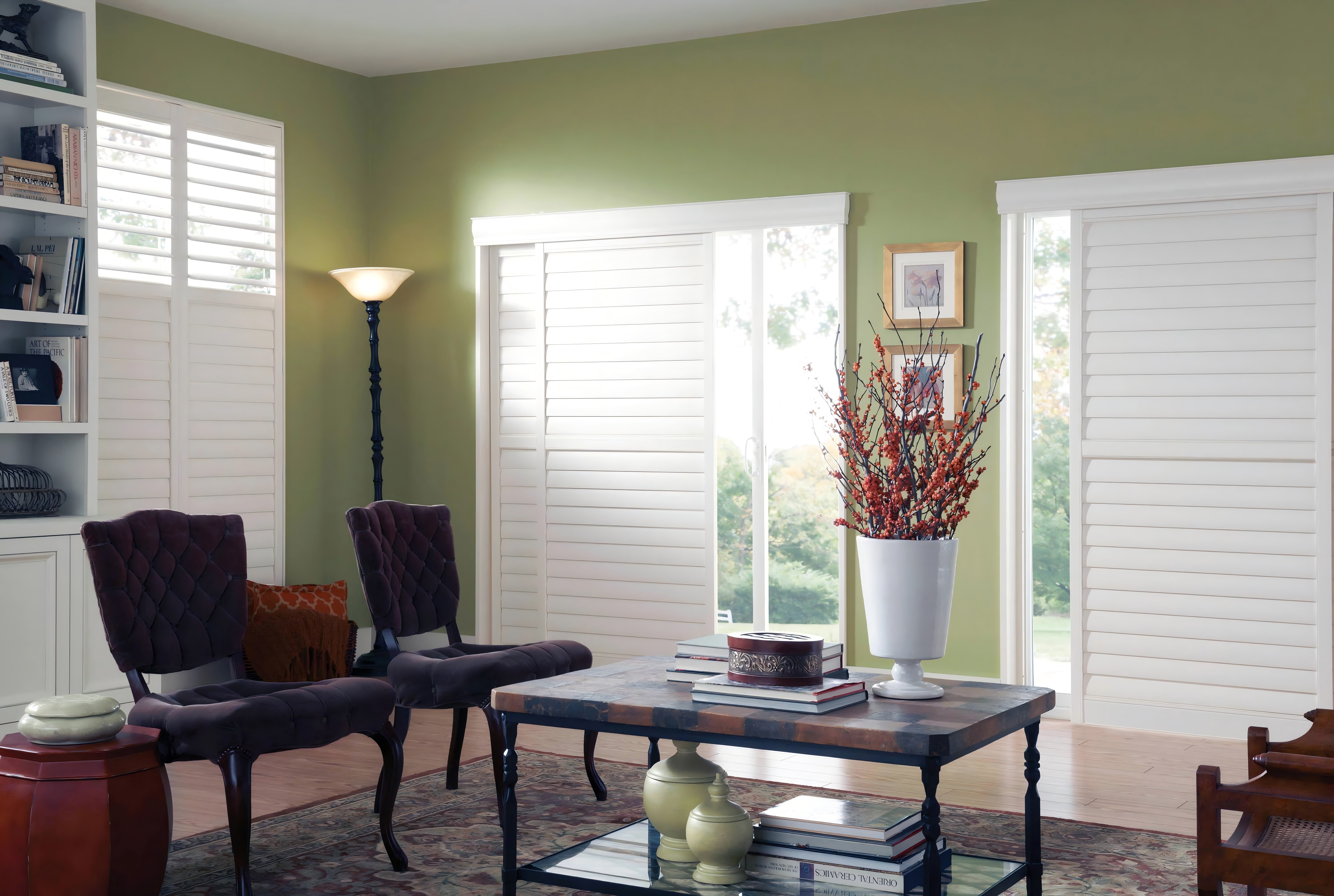 White bypass track shutters installed across a wide sliding glass door and adjacent windows