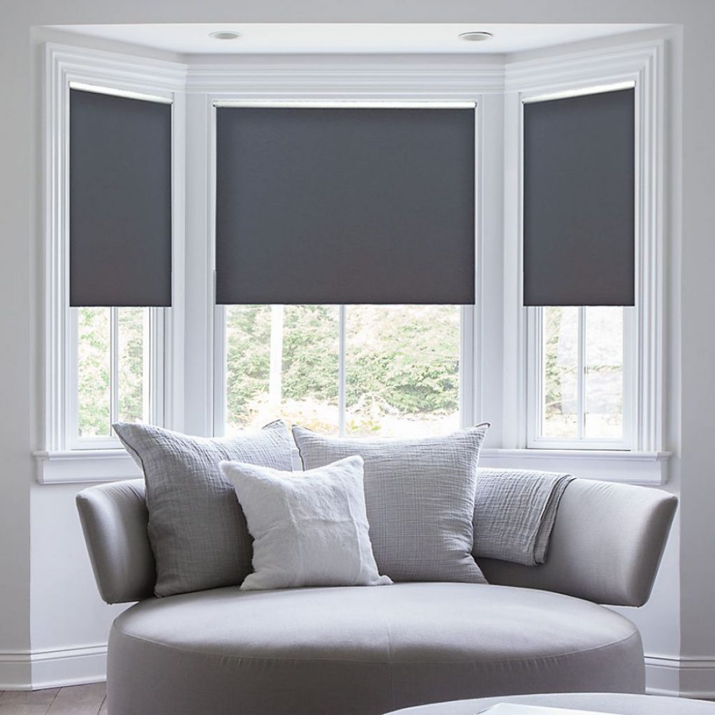 Dark roller shades installed in a bay window